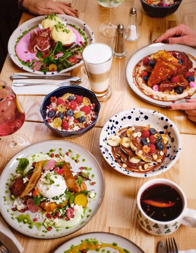 Gazdagon terített brunch asztal smoothie bowl-okkal, buggyantott tojással, palacsintával, pékáruval, lattéval és frissítő italokkal – Coni Brunch and Bar reggeli kínálata társaságnak